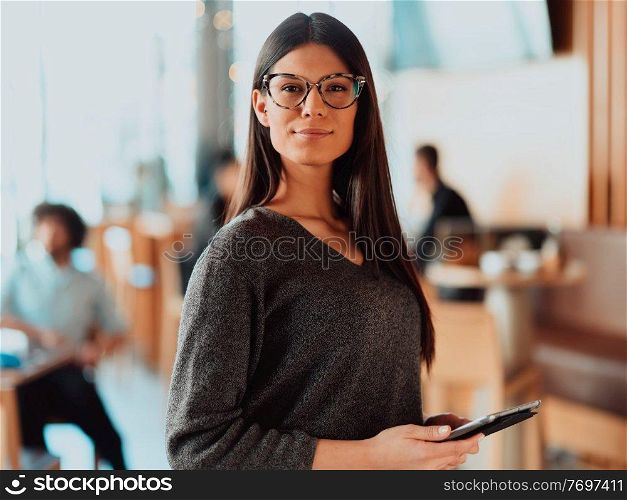 Portrait of happy smiling beautiful businesswoman holding tablet. Portrait of pretty young businesswoman looking at camera while holding digital tablet standing in the office..