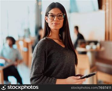 Portrait of happy smiling beautiful businesswoman holding tablet. Portrait of pretty young businesswoman looking at camera while holding digital tablet standing in the office..