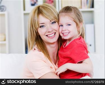 Portrait of happy smiling cheerful mother with daughter in embracing - indoors