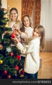 Portrait of happy smiling family decorating Christmas tree at living room