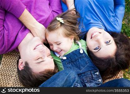 Portrait of happy smiling family lying outdoors in autumn park
