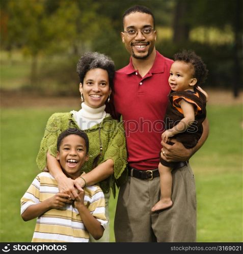 Portrait of happy smiling family of four in park.