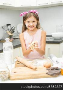 Portrait of happy smiling girl making dough for pie on kitchen
