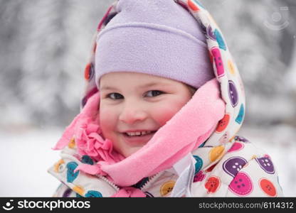 portrait of happy smiling little girl outdoors, having fun and playing on fresh snow on snowy winter day