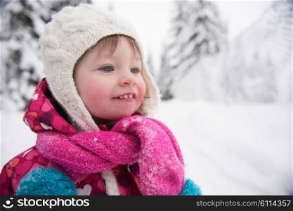 portrait of happy smiling little girl outdoors, having fun and playing on fresh snow on snowy winter day
