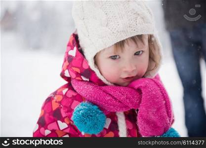 portrait of happy smiling little girl outdoors, having fun and playing on fresh snow on snowy winter day