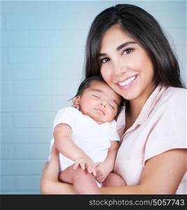 Portrait of happy smiling mother with cute sleeping baby on hands, spending time at home, loving family concept