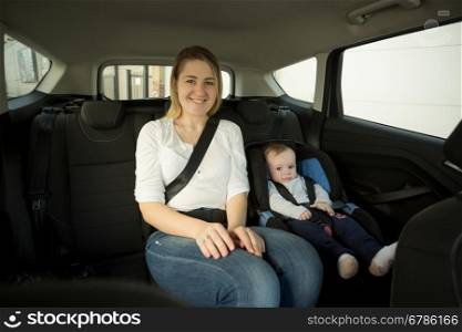 Portrait of happy smiling mother with her baby on back seat