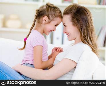 Portrait of happy smiling mother with her little daughter at home - indoors