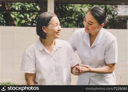 Portrait of happy smiling nurse helping mature elderly standing and walking in a nursing house. Nursing home, Hospital, health, care, nurse Concept.