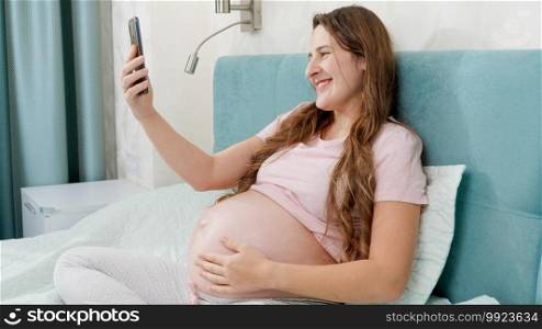 Portrait of happy smiling pregnant woman having video talk or conference on smartphone. Portrait of happy smiling pregnant woman having video talk or conference on smartphone.