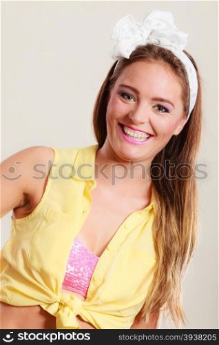 Portrait of happy smiling pretty pin up girl with hairband bow. Attractive gorgeous young retro woman posing in studio.