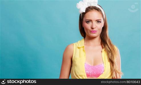 Portrait of happy smiling pretty pin up girl with hairband bow. Attractive gorgeous young retro woman posing in studio on blue background.