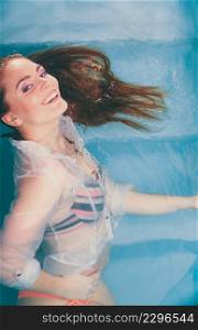 Portrait of happy smiling seductive woman floating in swimming pool water. Pretty sexy alluring young girl wearing wet white shirt.. Happy smiling sexy seductive woman in water.