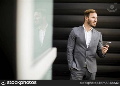 Portrait of happy smiling urban businessman using smart phone outside