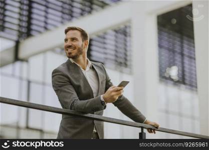 Portrait of happy smiling urban businessman using smart phone outside