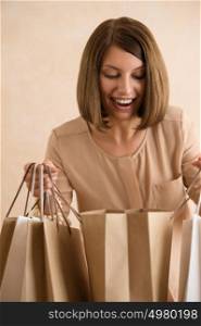Portrait of happy smiling woman holding shopping bags looking inside