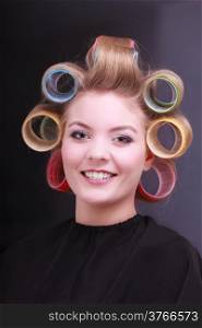 Portrait of happy smiling woman in beauty salon. Blond girl with hair curlers rollers by hairdresser. Hairstyle.