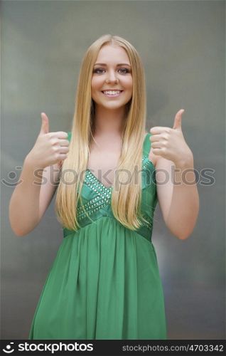 Portrait of happy smiling young beautiful woman in white casual clothing, showing thumbs up gesture, over white background