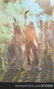 Portrait of happy smiling young girls with colorful paints on faces and clothes. Two friends spending time on holi color festival