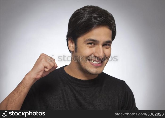 Portrait of happy smiling Young man gesturing victory with clenched fist