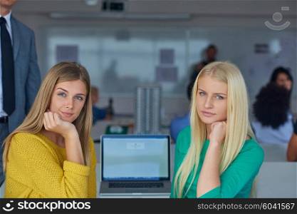 portrait of happy student girls together in classroom, laptop computer in background