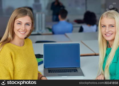 portrait of happy student girls together in classroom, laptop computer in background