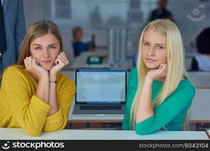 portrait of happy student girls together in classroom, laptop computer in background