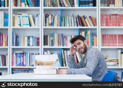 Portrait of happy student while reading book in school library. Study lessons for exam. Hard worker and persistance concept.