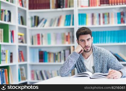 Portrait of happy student while reading book in school library. Study lessons for exam. Hard worker and persistance concept.