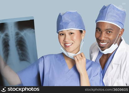 Portrait of happy surgeons holding x-ray report over light blue background