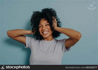 Portrait of happy surprised young woman looking excited in full disbelief with hands on head showing wow! no way? gesture, isolated on blue background. Positive human emotions concept. Portrait of happy surprised young woman looking excited in full disbelief with hands on head