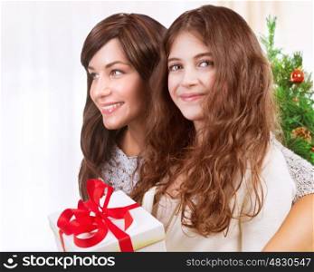Portrait of happy teen girl with her beautiful young mother celebrating winter holidays at home, enjoying Christmas present