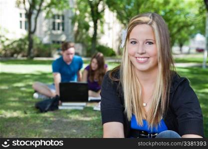 Portrait of happy teenage girl with classmates in background