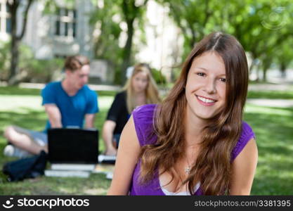 Portrait of happy teenage girl with classmates in background