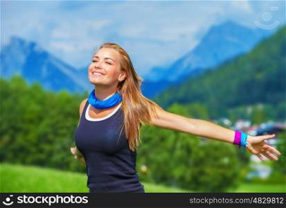 Portrait of happy traveler girl with raised up hands enjoying sunny day, mountains landscape, travel to Europe, happiness emotion, summer holiday concept