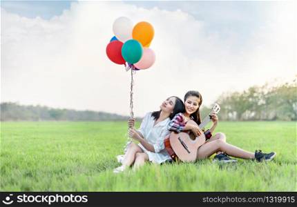 Portrait of happy two women relaxing in green field. happy pretty women with balloons