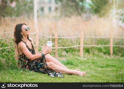Portrait of happy urban girl relaxing outdoor. Beautiful woman on holidays in the park. Happy young urban woman drinking coffee in european city.