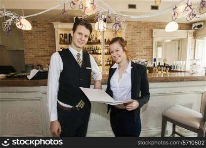 Portrait of happy waiter and waitress in restaurant