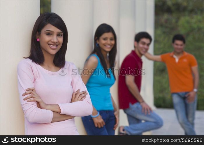 Portrait of happy woman and friends leaning on columns outdoors