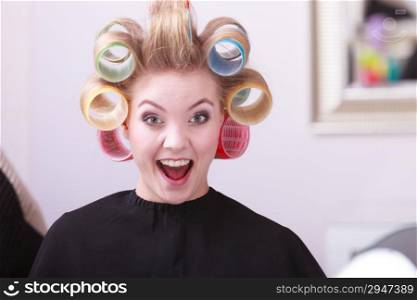 portrait of happy woman at beauty salon. cheerful blond girl with hair curlers rollers by hairdresser. hairstyle.