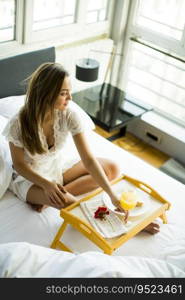 Portrait of happy woman eating breakfast in bed, smiling and healthy