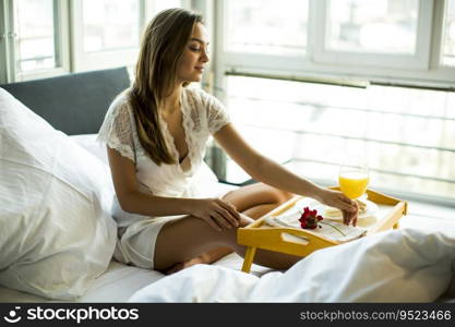 Portrait of happy woman eating breakfast in bed, smiling and healthy