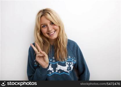 Portrait of happy woman gesturing peace sign against white background