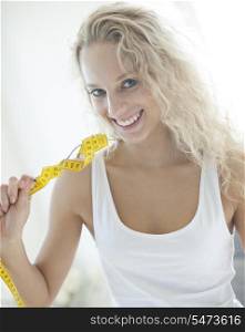 Portrait of happy woman holding fork wrapped with measuring tape