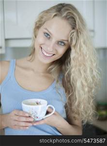 Portrait of happy woman holding tea cup in house