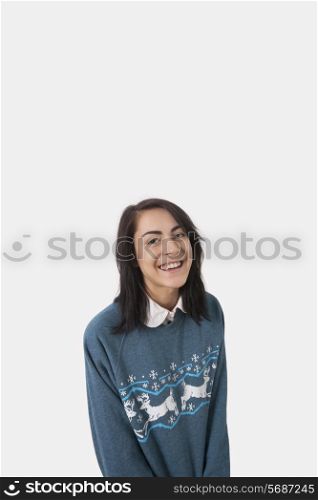 Portrait of happy woman in Christmas jumper against gray background