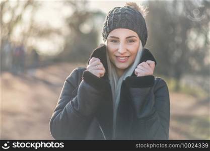 Portrait of happy woman in warm clothing on winter day outdoors. Cheerful girl wearing wool cap and black jacket. Winter and happiness concept. Female person in cold weather.
