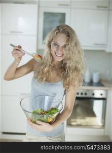 Portrait of happy woman mixing salad in kitchen