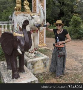 Portrait of happy woman standing near elephant sculpture at temple, Siem Reap, Cambodia